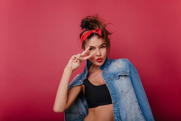 Sporty winsome girl with tanned skin posing with peace sign