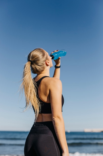 Free photo sporty woman drinking at the beach