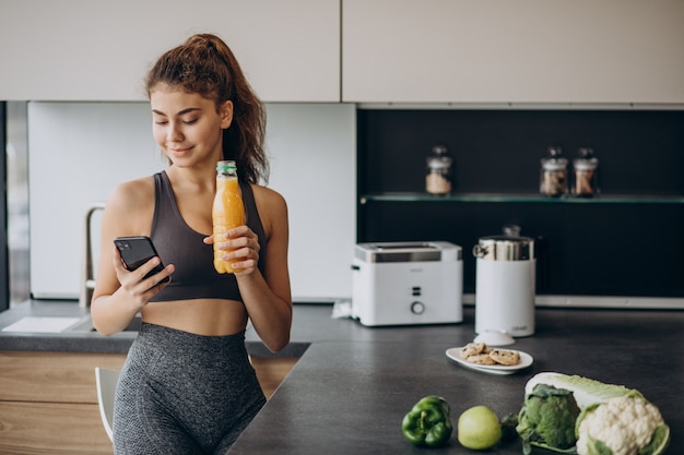 Free photo sporty woman at kitchen using mobile phone