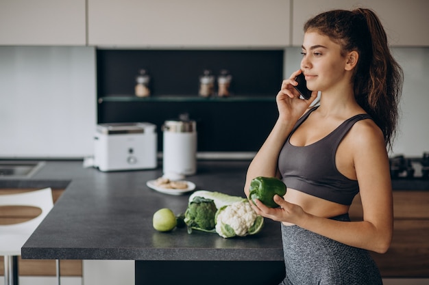 Free photo sporty woman at kitchen using mobile phone