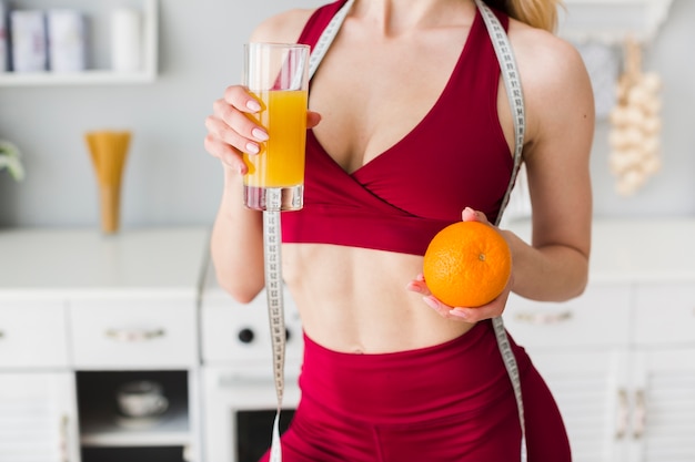 Free photo sporty woman in kitchen with healthy juice