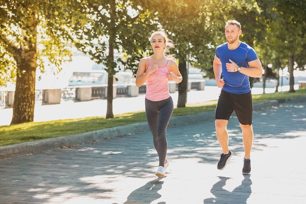 Free photo the sporty woman and man jogging at park in sunrise light