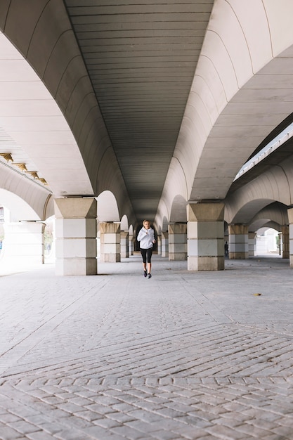 Sporty woman running near columns