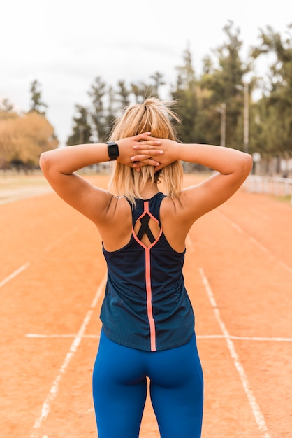 Free photo sporty woman standing on stadium track