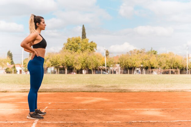 Sporty woman standing on stadium track