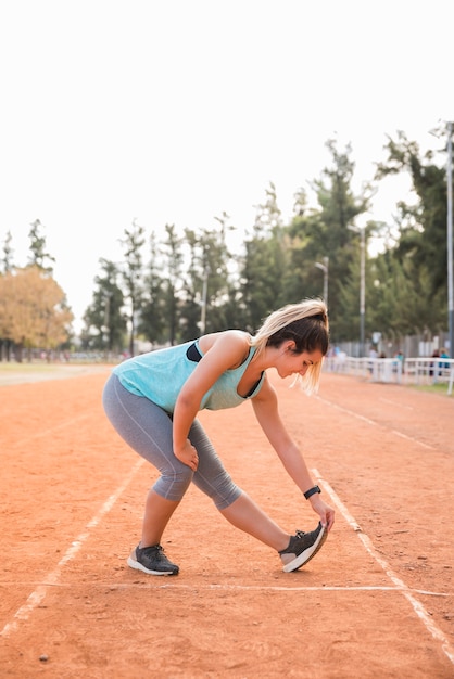 Sporty woman stretching on stadium track