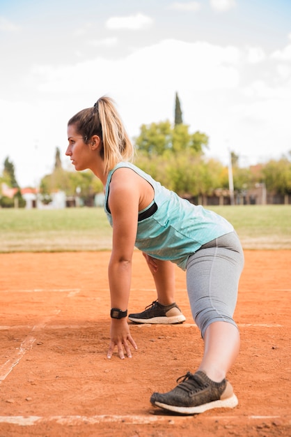 Sporty woman stretching on stadium track