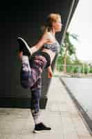 Free photo sporty woman stretching in urban environment