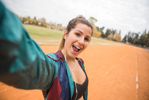 Sporty woman taking selfie on stadium track