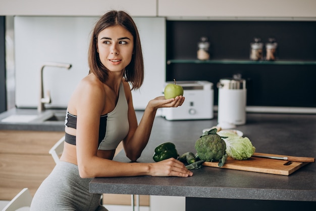 Free photo sporty woman with apple at the kitchen