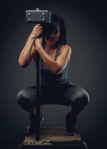 Free photo sporty woman with short black hair sitting on wooden box and holding big black hummer.