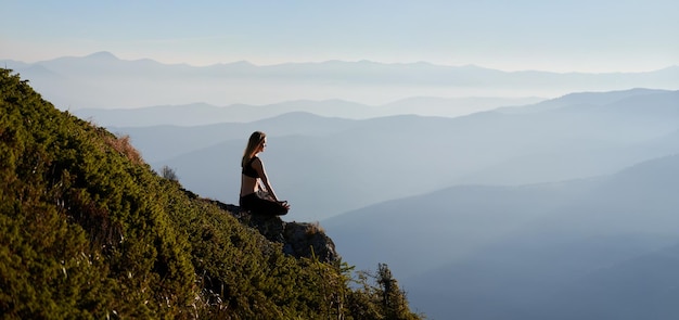 Free Photo sporty young woman meditating in mountains