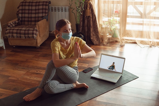 Free photo sporty young woman taking yoga lessons online and practice at home while being quarantine.