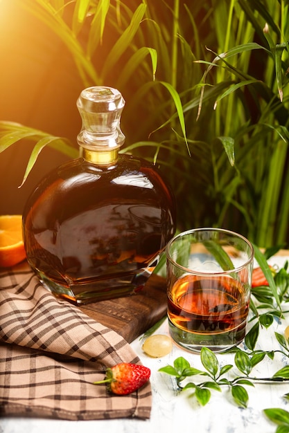 A spotlight on a crystal glass of brandy with fruits and greenery, shot on a wooden table top