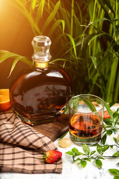 A spotlight on a crystal glass of brandy with fruits and greenery, shot on a wooden table top