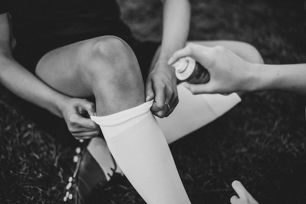 Free photo spraying cooling spray on a football players knee