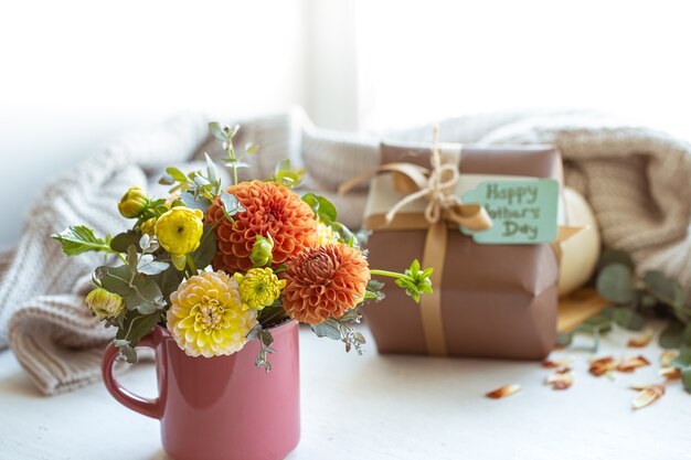 Spring composition for mother's day with gift, chrysanthemum flowers and knitted element.