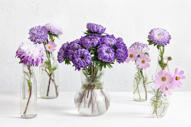 Spring composition with chrysanthemum flowers in glass vases on a blurred white background.