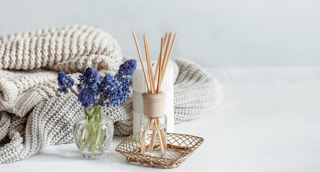 Free photo spring home composition with flowers, aroma sticks and knitted element copy space.