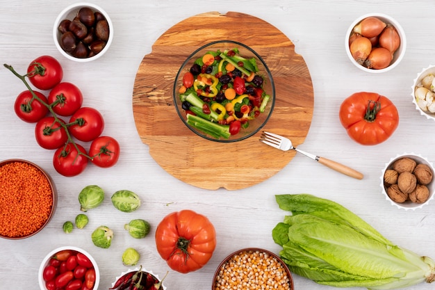 Spring salad on the wooden board surrounded by different fresh vegetables