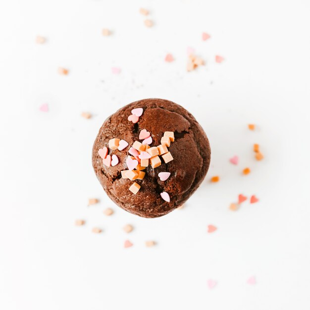 Sprinkle and caramel candies on chocolate cupcake isolated on white background