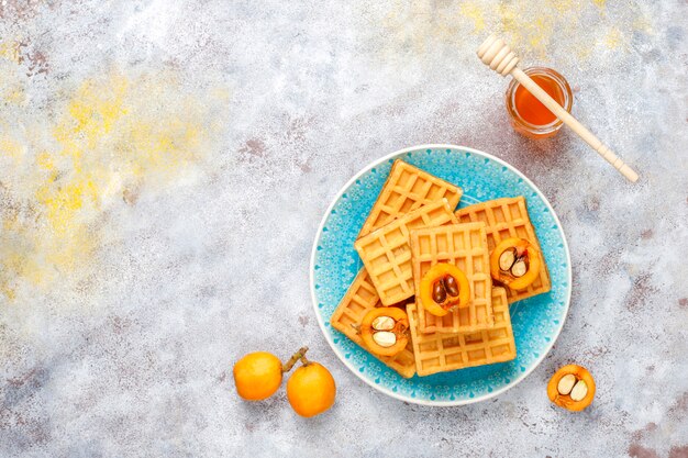 Square belgian waffles with loquat fruits and honey.