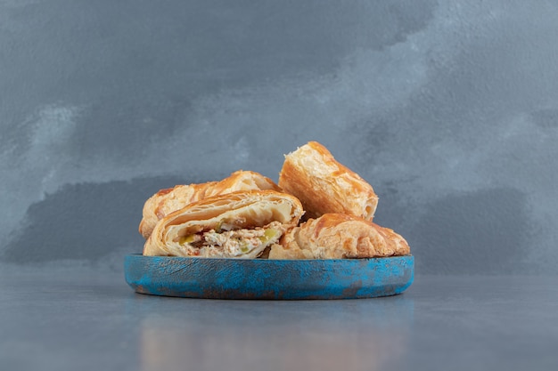 Square shaped stuffed pastries on blue plate.