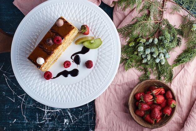 Free Photo square slice of caramel cake with strawberries, top view. 