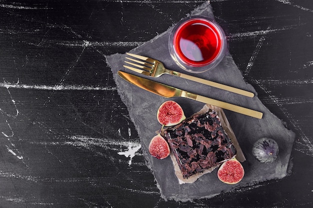 A square slice of chocolate cheesecake with red drink