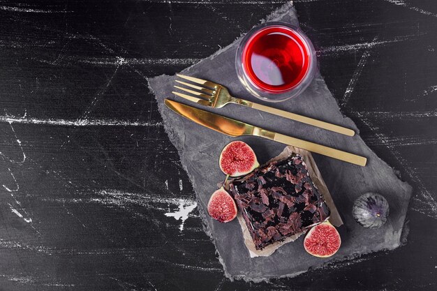 A square slice of chocolate cheesecake with red drink