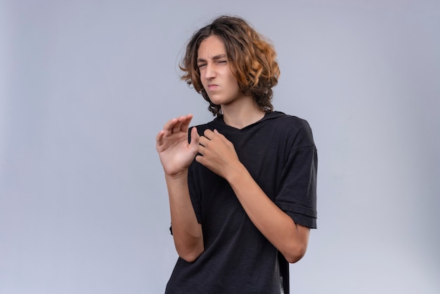 Free photo squeamish guy with long hair in black t-shirt on white background