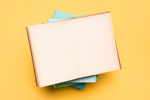 Stack of books and open notepad with blank pages 