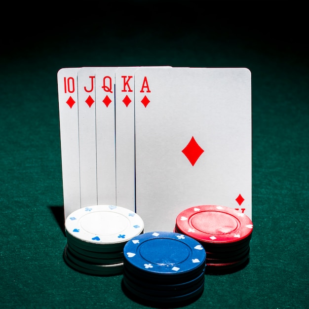 Free photo stack of casino chips in front of royal flush playing card on poker table