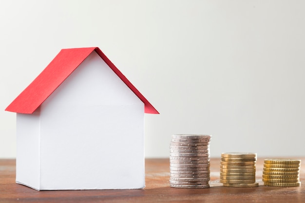 Stack of coins with miniature bank beside