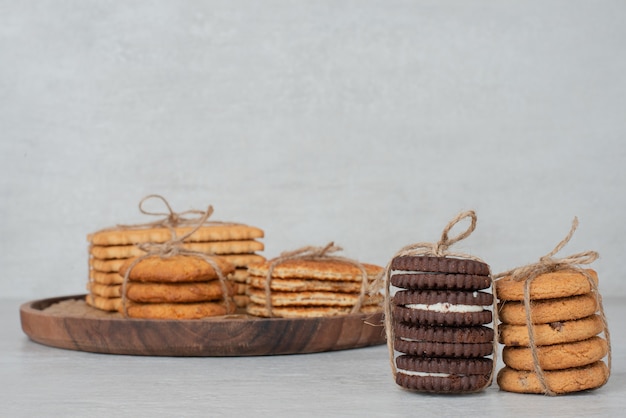 Stack of cookies tied with rope on wooden plate. 