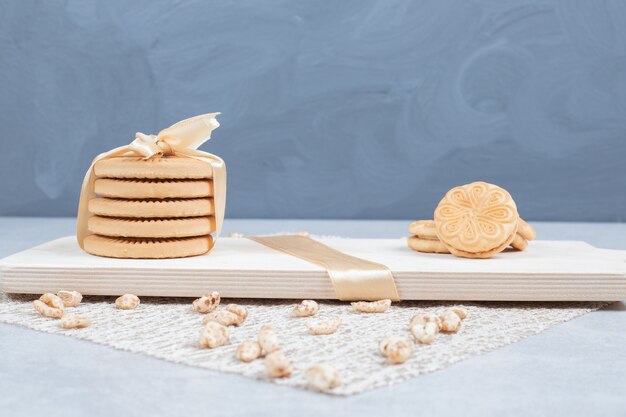 Stack of festive biscuits and peanuts on wooden board. 