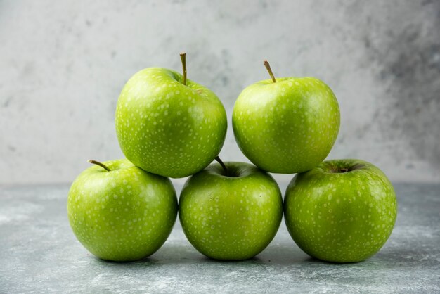 Stack of fresh apples on marble.