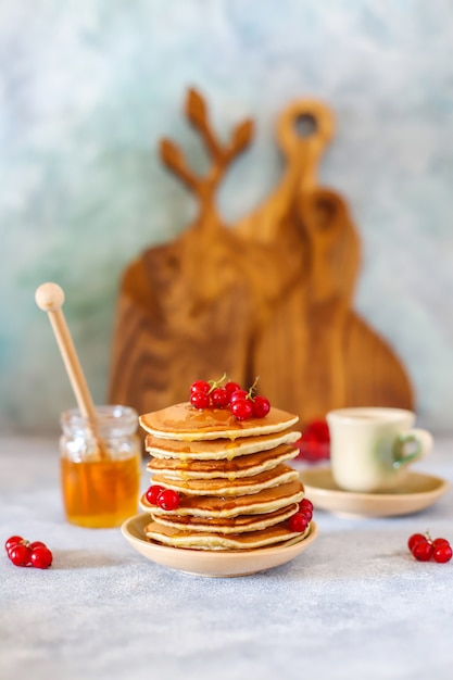 Free photo stack of homemade pancakes with honey syrup and berries.