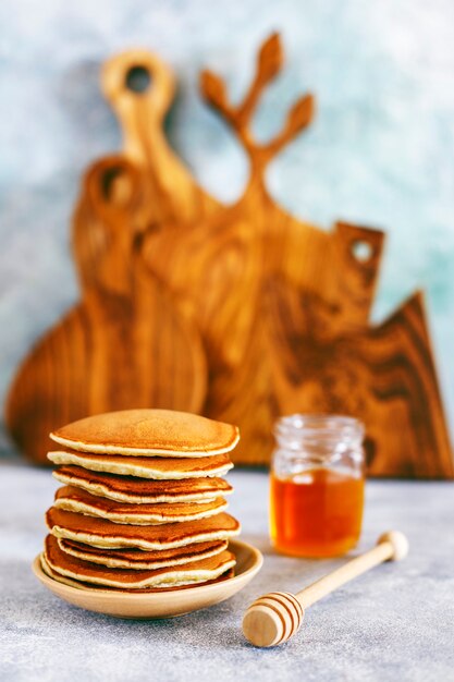 Stack of homemade pancakes with honey syrup and berries.