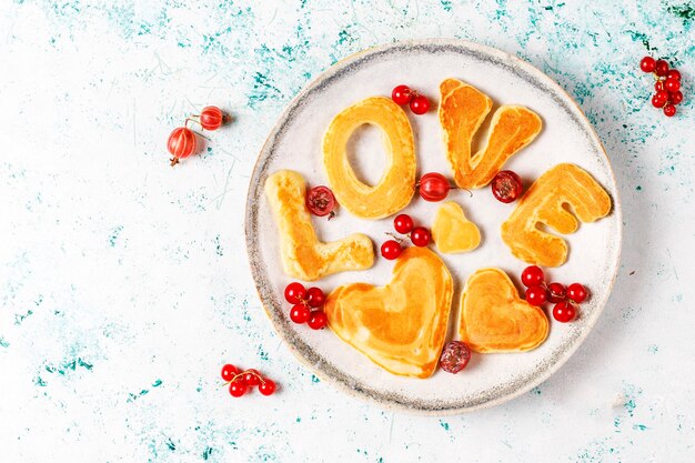 Stack of homemade pancakes with honey syrup and berries.