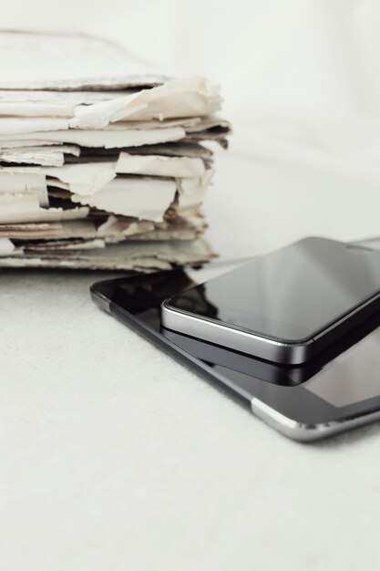 Stack of newspapers with digital tablet and smartphone