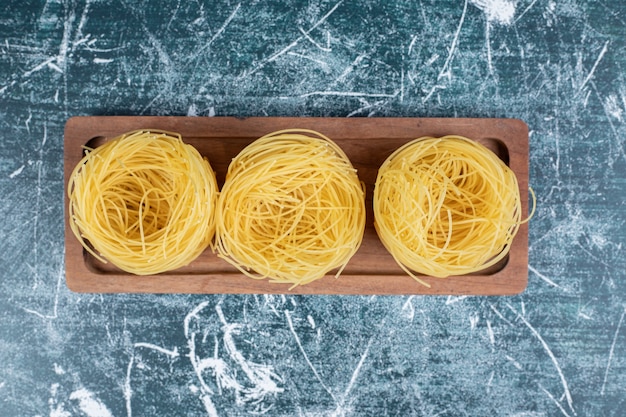 Stack of raw spaghetti nests on wooden board. High quality photo