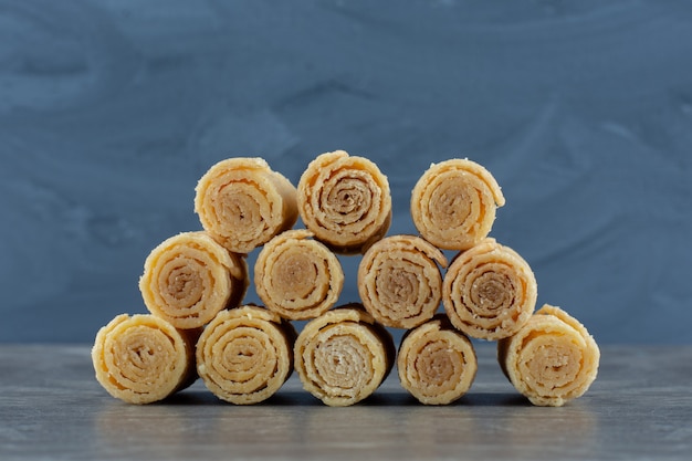 Stack of rolled waffles on grey table.