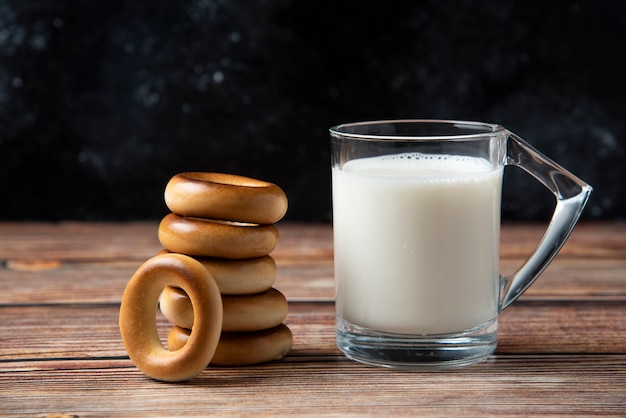 Stack of round biscuits and glass of milk on wooden table. 