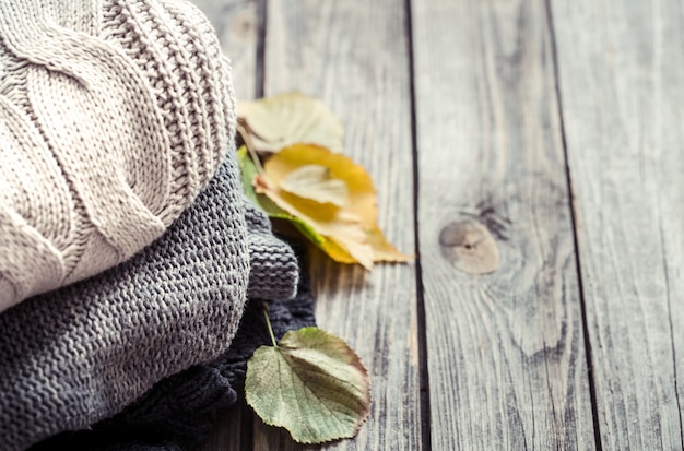 a stack of sweaters and autumn leaves