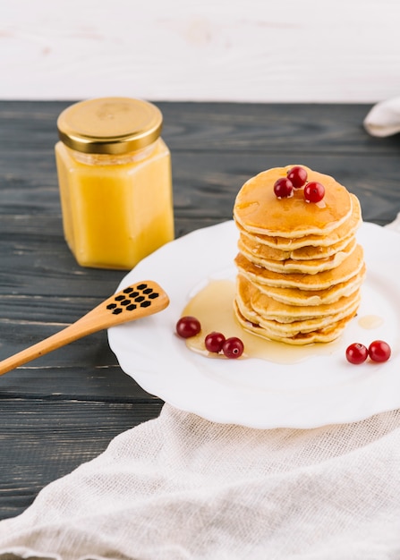 Free photo stacked of pancake with honey and red currant berries on plate