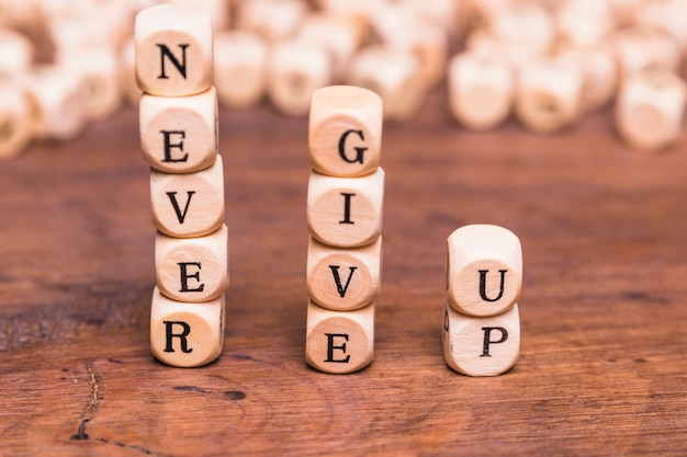 Free photo stacked of wooden blocks with word never give up on wooden desk