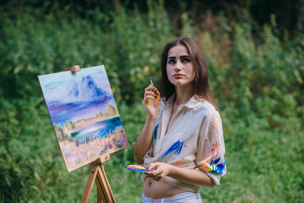 Free photo stained woman painting with a picture behind