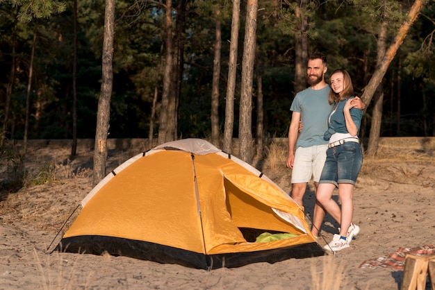 Standing couple by a tent looking away