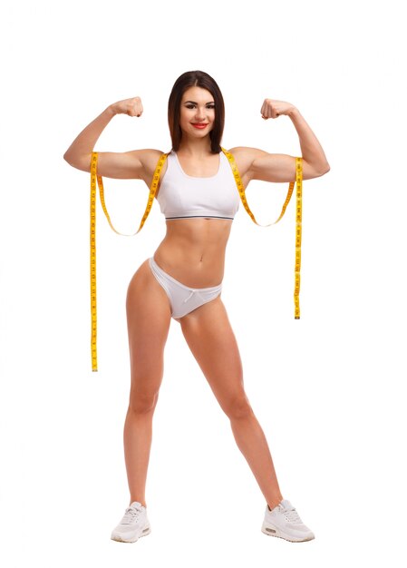 Standing woman squeezing both biceps and a tape measure